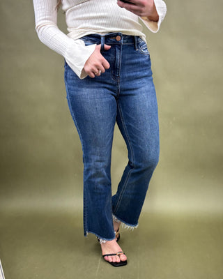 Person wearing blue jeans and a white sweater on a plain background