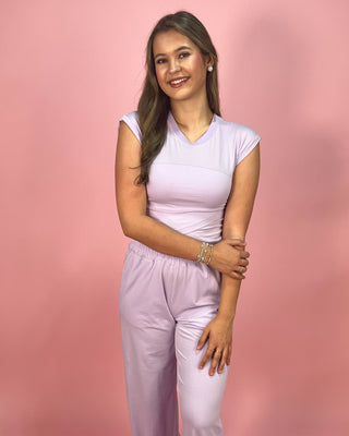 Woman wearing a light purple outfit against a pink background