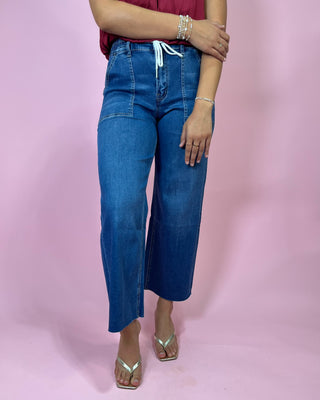 Person wearing blue jeans on a pink background