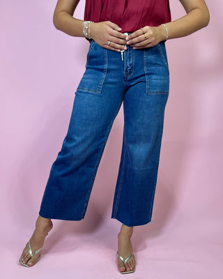 Person wearing blue jeans and a red top on a pink background