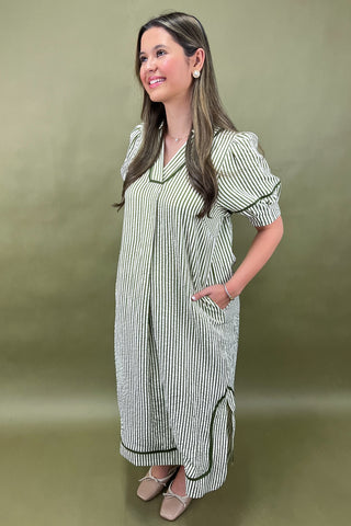 Woman wearing a green and white striped dress against a beige background