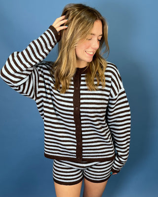 A woman modeling a matching brown and white striped knit cardigan and shorts set