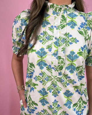 Woman wearing a floral dress with blue and green leaves on a pink background