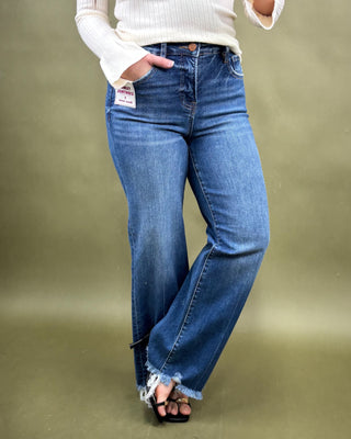 Person wearing blue jeans with a white sweater on a green background