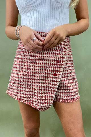 Person wearing a red and white checkered skirt with a plain background
