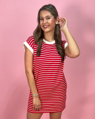 Woman wearing a red and white striped dress against a pink background