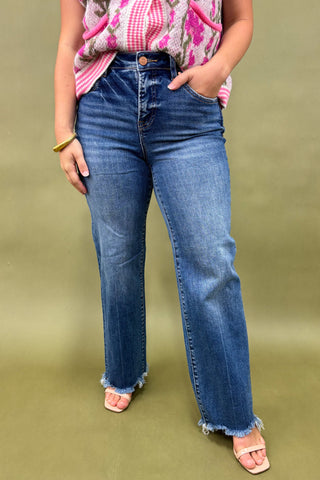 Person wearing blue jeans and a colorful top on a green background