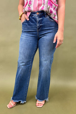Person wearing blue jeans and a pink floral top on a green background