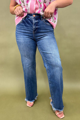 Person wearing blue jeans and a floral top on a green background