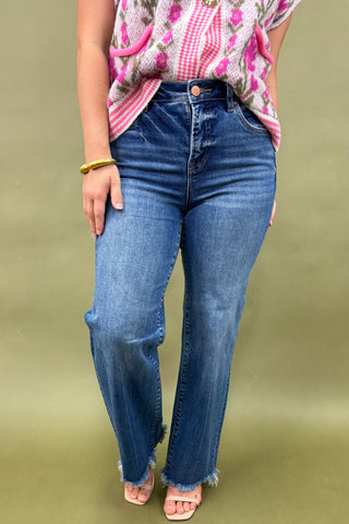 Person wearing blue jeans and a pink floral top on a green background