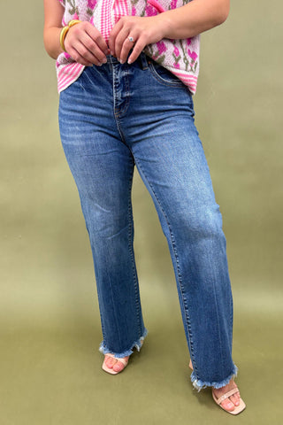 Person wearing blue jeans and a floral top on a green background