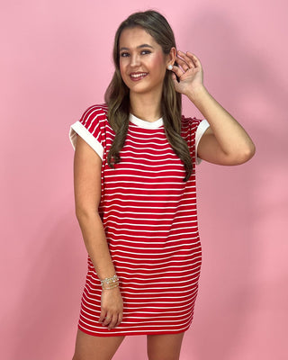 Woman wearing a red and white striped dress against a pink background