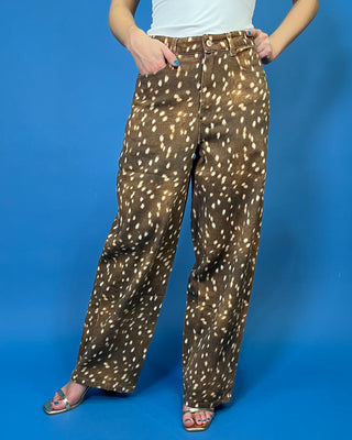 A person wearing wide-leg brown pants with a white spotted animal print, paired with a white top and metallic sandals