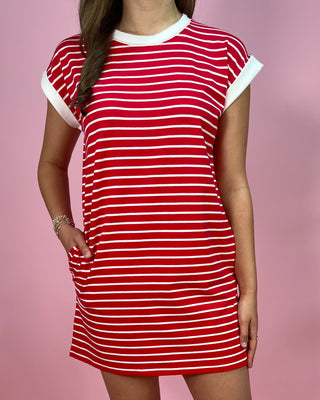 Red and white striped dress worn by a person on a pink background