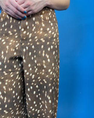 A close-up of a person wearing brown wide-leg pants with an allover white spotted pattern