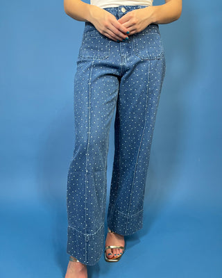 A person wearing blue denim jeans with a white polka-dot pattern