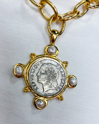 Gold necklace with a coin and pearl pendant on a white background