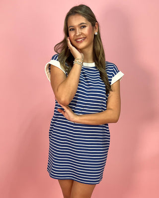 Woman wearing a blue and white striped dress against a pink background