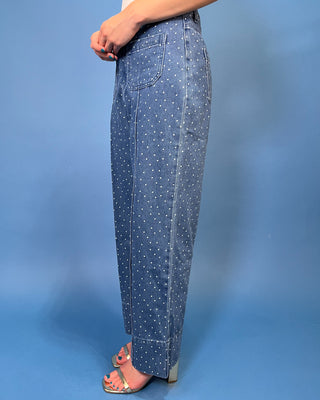 A person wearing wide-leg blue denim jeans with a white polka-dot pattern, paired with clear high-heeled sandal