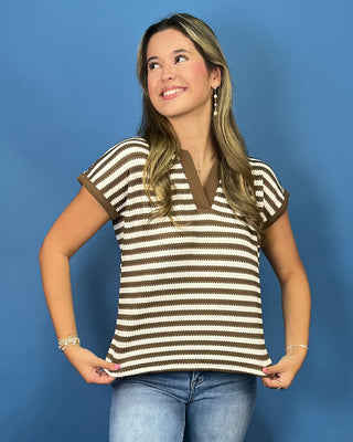 A woman modeling a brown and cream striped short-sleeve knit top with a V-neck, paired with blue jean