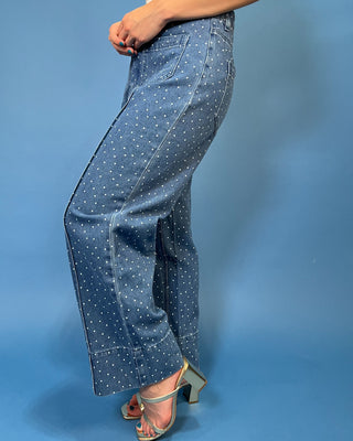 A person wearing blue denim wide-leg pants with a white polka dot pattern