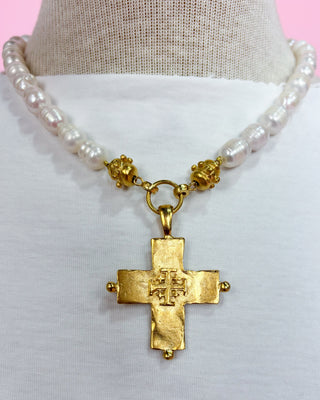 Necklace with gold cross pendant and pearl beads on a mannequin.
