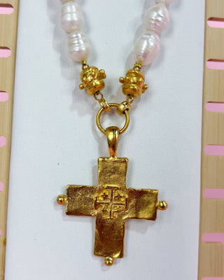 Necklace with gold cross pendant and pearl beads on a white background