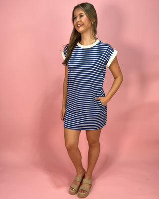 Woman wearing a blue and white striped dress against a pink background