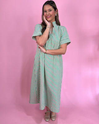 Woman wearing a green and white striped dress against a pink background