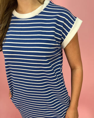 Blue and white striped dress worn by a person on a pink background