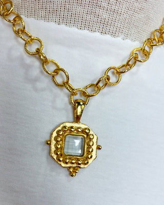 Gold chain necklace with a decorative pendant on a white background