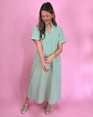 Woman wearing a green and white striped dress against a pink background