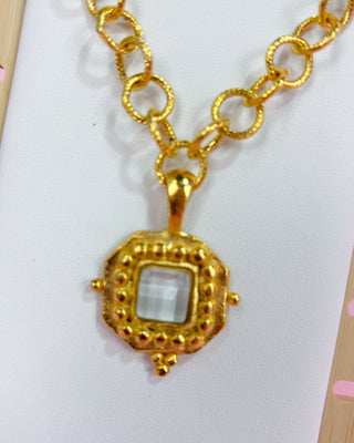 Gold necklace with a square pendant on a white background