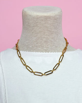 Gold chain necklace on a mannequin with a pink background