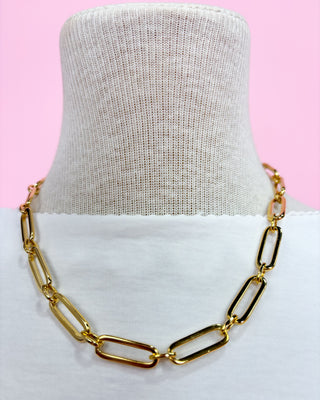 Gold chain necklace on a mannequin with a pink background