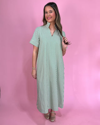 Woman wearing a green and white striped dress against a pink background