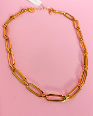 Gold chain necklace on a pink background