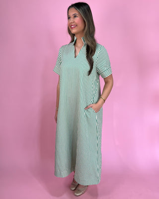 Woman wearing a green and white striped dress against a pink background