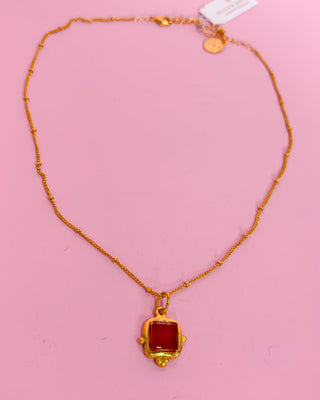 Necklace with a red pendant on a pink background