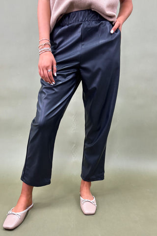 Person wearing navy pants and light pink shoes on a plain background