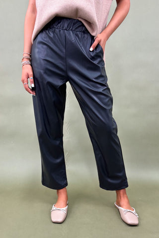 Person wearing navy pants and light pink shoes on a plain background