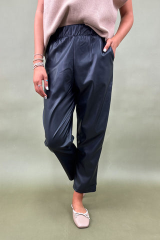 Person wearing navy blue pants and a light pink top on a plain background