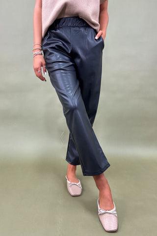 Person wearing navy blue pants and pink shoes on a plain background