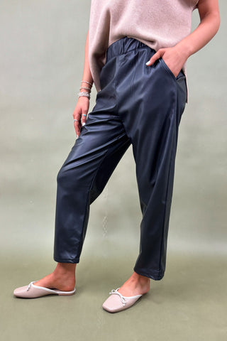 Person wearing navy pants and a light pink top against a plain background