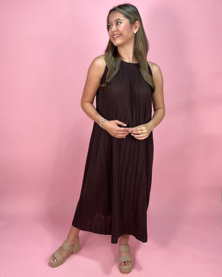 Woman wearing a brown dress against a pink background