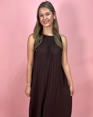 Woman wearing a brown dress against a pink background