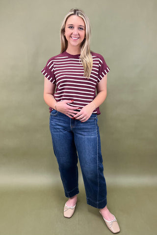 Woman wearing a striped shirt and jeans against a plain background