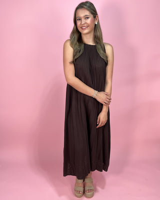 Woman wearing a brown dress against a pink background