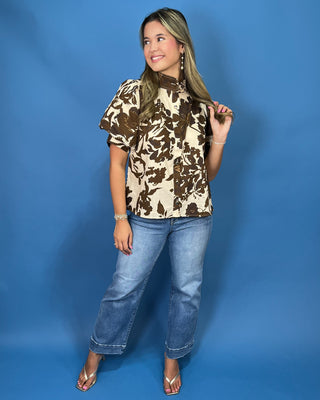A woman modeling a short-sleeve floral print blouse with a high mock neck