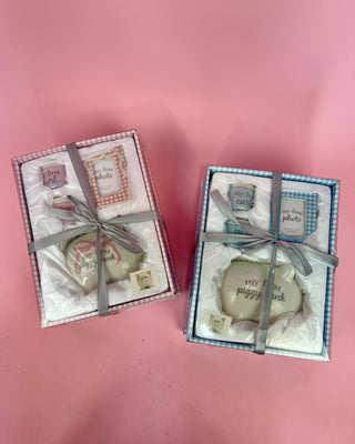 Two small gift boxes with decorative items on a pink background